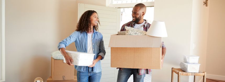 Couple carrying boxes into new home